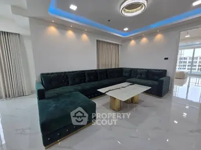 Luxurious living room with elegant green sectional sofa and marble coffee table, featuring modern lighting and glossy floors.