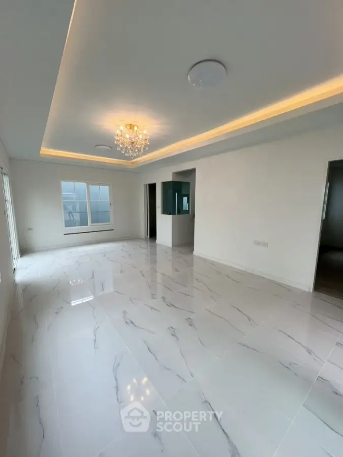 Spacious modern living room with elegant chandelier and glossy marble flooring.