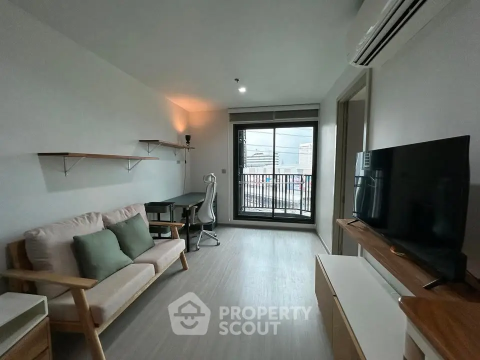 Modern living room with balcony view, featuring sleek furniture and ample natural light.