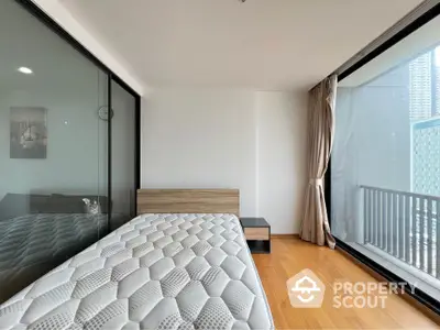 Modern bedroom with floor-to-ceiling windows and hardwood floors, offering a bright and airy atmosphere.