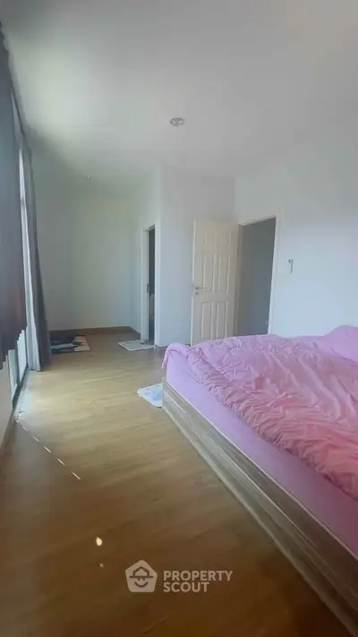 Spacious bedroom with pink bedding and natural light