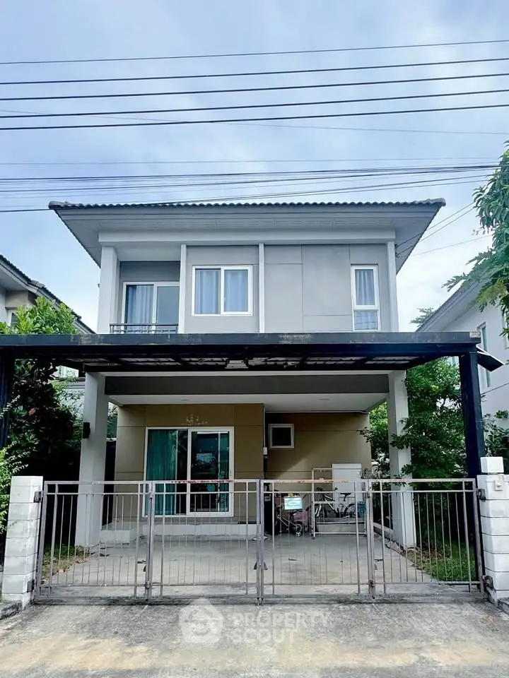 Modern two-story house with gated driveway and lush greenery, perfect for family living.