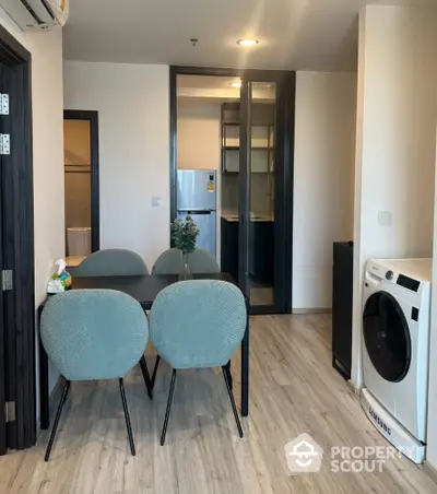 Modern apartment interior with dining area and washing machine, featuring sleek design and contemporary furnishings.