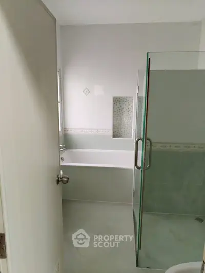 Modern bathroom with glass shower and bathtub, elegant tile design.