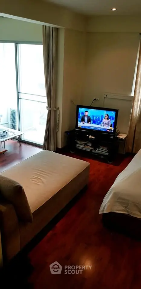 Cozy living room with modern decor and natural light, featuring a comfortable sofa and flat-screen TV.