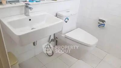 Modern bathroom with sleek white fixtures and tiled walls.