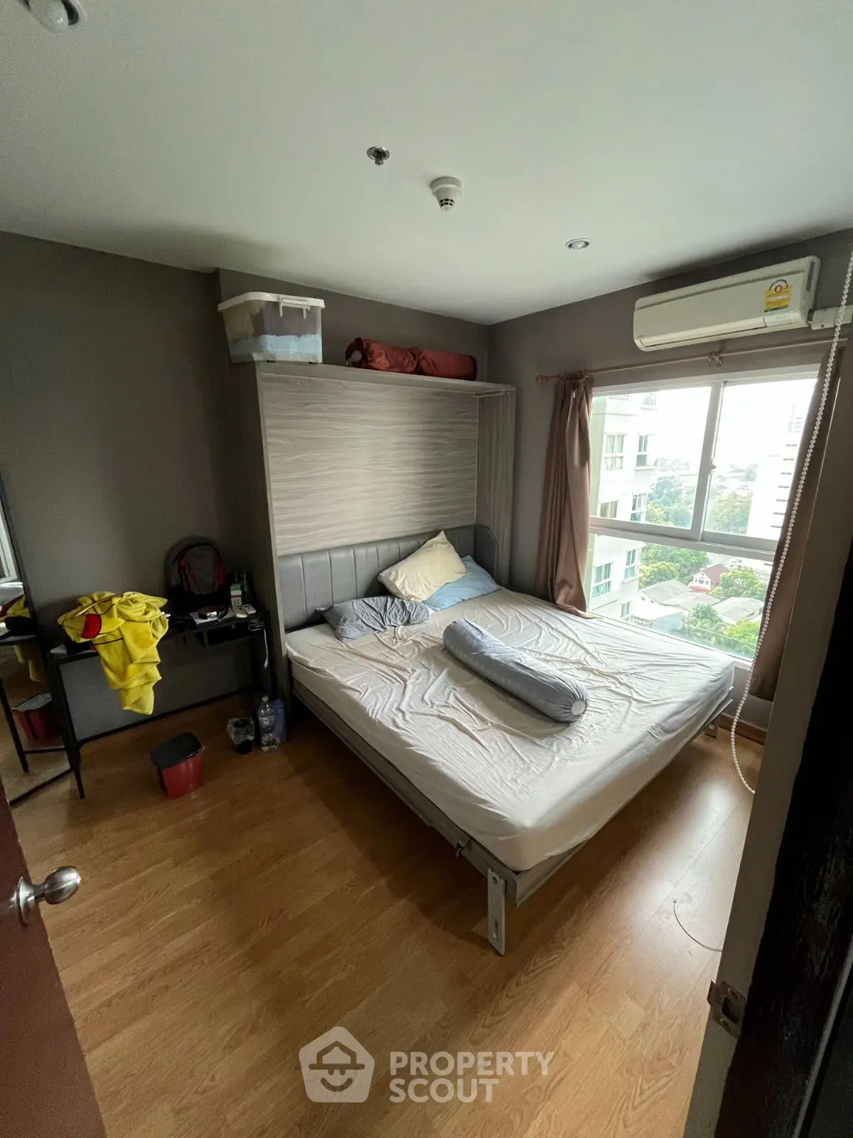 Cozy bedroom with large window and wooden flooring, featuring a comfortable bed and modern decor.