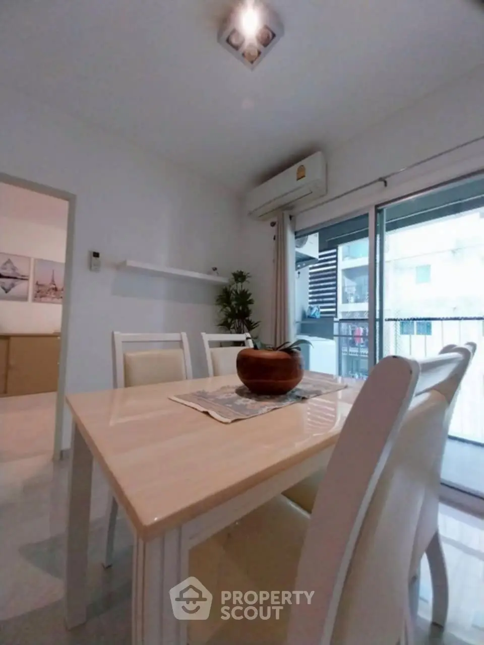 Modern dining area with sleek table and chairs, adjacent to balcony with natural light.