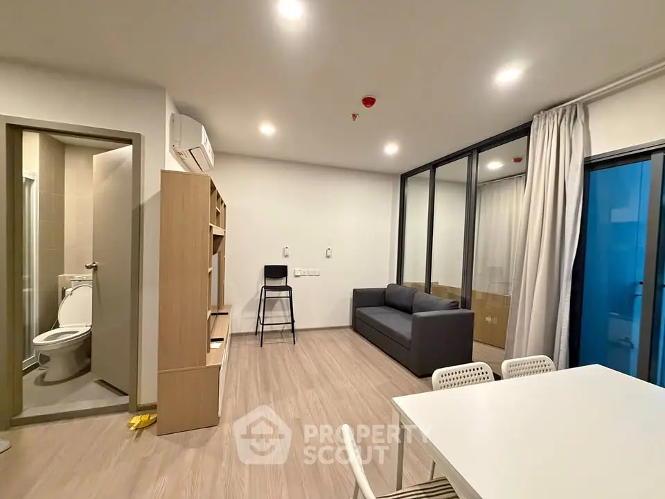 Modern living room with sleek furniture and open layout, featuring a cozy sofa and dining area.