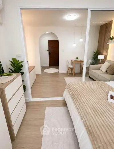 Modern bedroom with cozy decor and open view to living area, featuring stylish furniture and warm lighting.