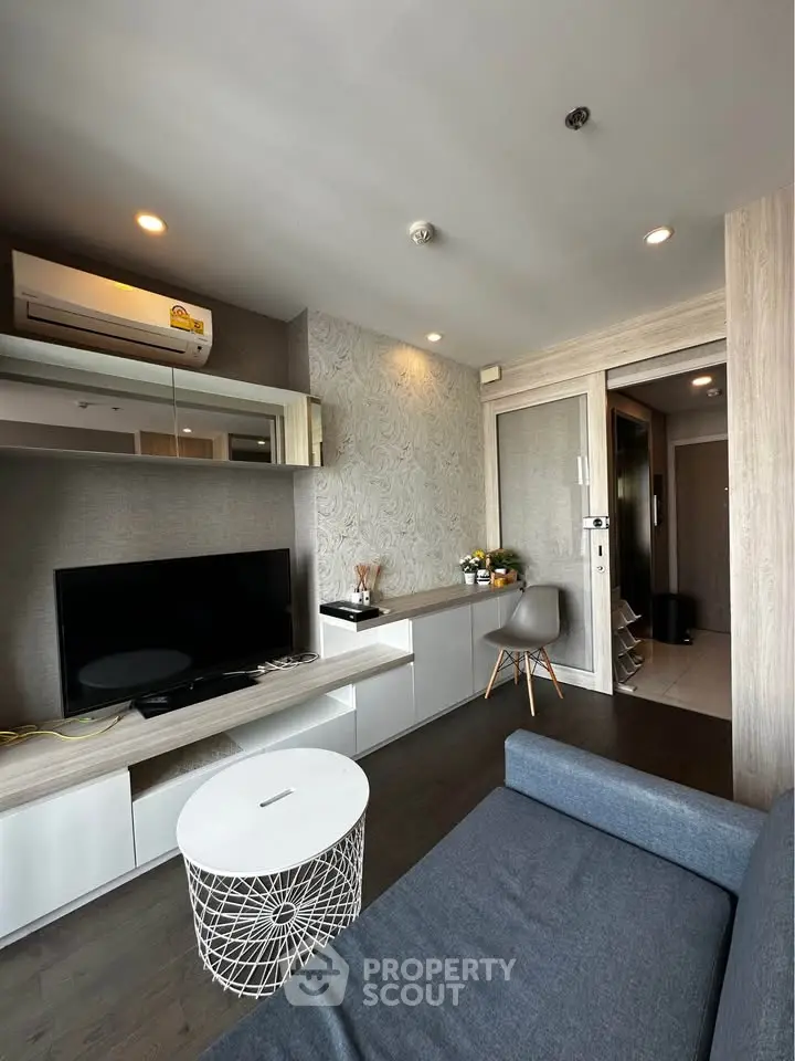 Modern living room with sleek design, featuring a comfortable sofa, flat-screen TV, and stylish decor.
