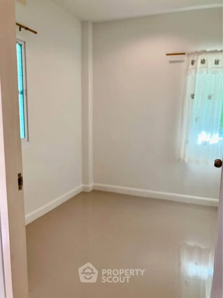 Spacious empty room with large window and neutral walls, perfect for customization.