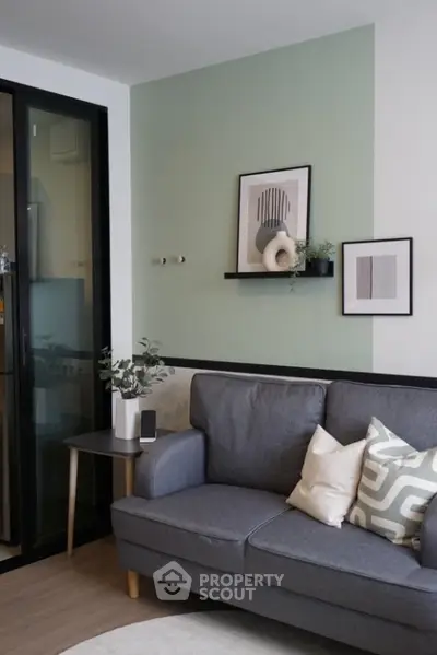 Modern living room with stylish decor and comfortable gray sofa, featuring minimalist wall art and cozy ambiance.