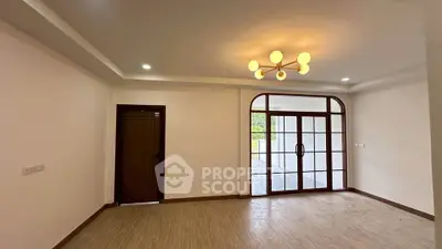 Spacious living room with elegant lighting and large windows opening to a balcony.
