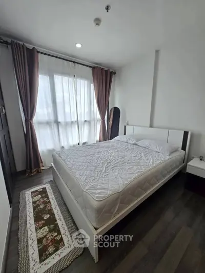 Modern bedroom with large window and stylish decor in a contemporary apartment.