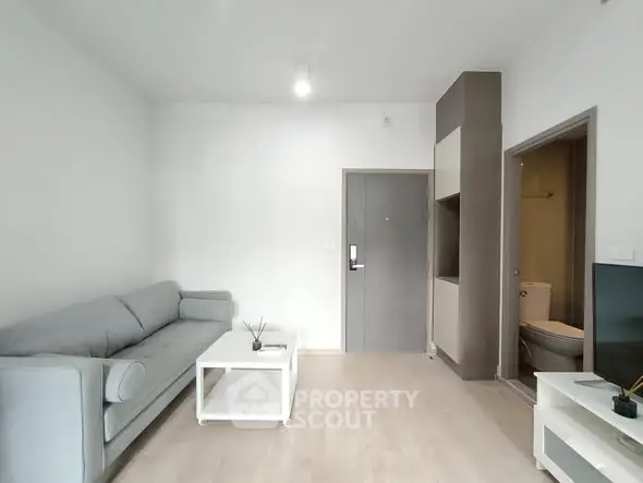 Modern living room with gray sofa and minimalist decor in a cozy apartment.