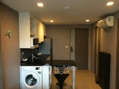 Modern kitchen with washing machine and sleek black countertop in stylish apartment.