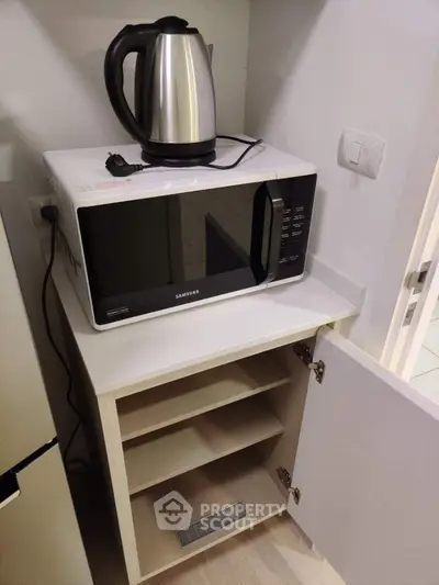 Modern kitchen corner with microwave and kettle on sleek white cabinet
