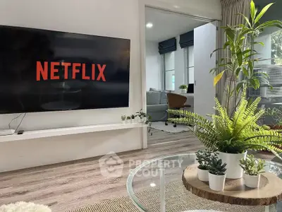 Modern living room with large TV and stylish decor, perfect for relaxation and entertainment.