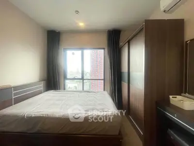 Spacious bedroom with large window offering city views, featuring modern furnishings and ample natural light.