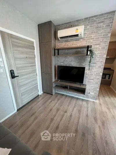 Modern living room with wood flooring, TV setup, and air conditioning in stylish apartment.