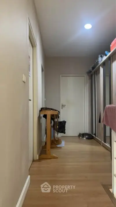 Spacious hallway with wooden flooring and ample storage space in modern apartment.