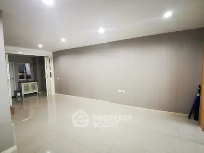 Spacious and well-lit living room with glossy tiled flooring, neutral wall colors, and recessed lighting, perfect for versatile interior design.