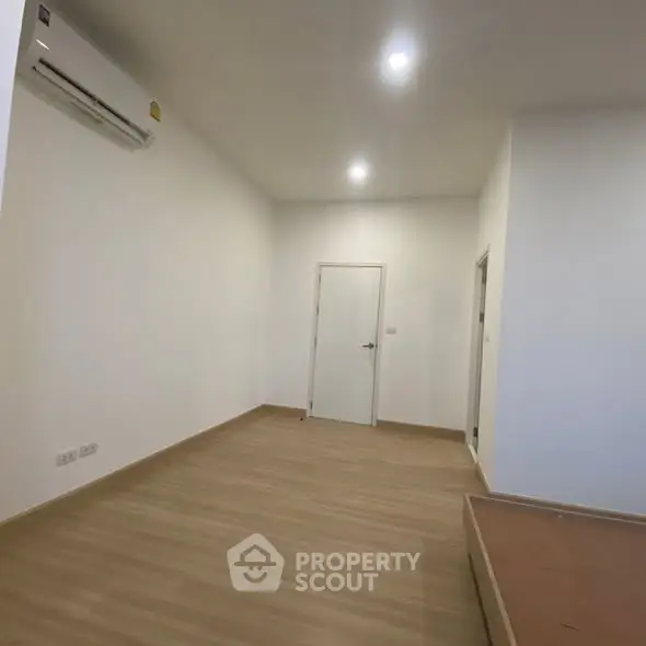 Spacious unfurnished room with wooden flooring and air conditioning unit.