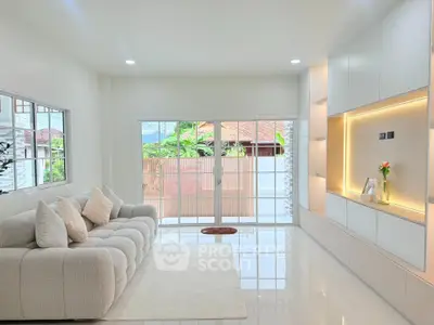 Spacious modern living room with elegant sofa and built-in shelves, featuring large windows and natural light.
