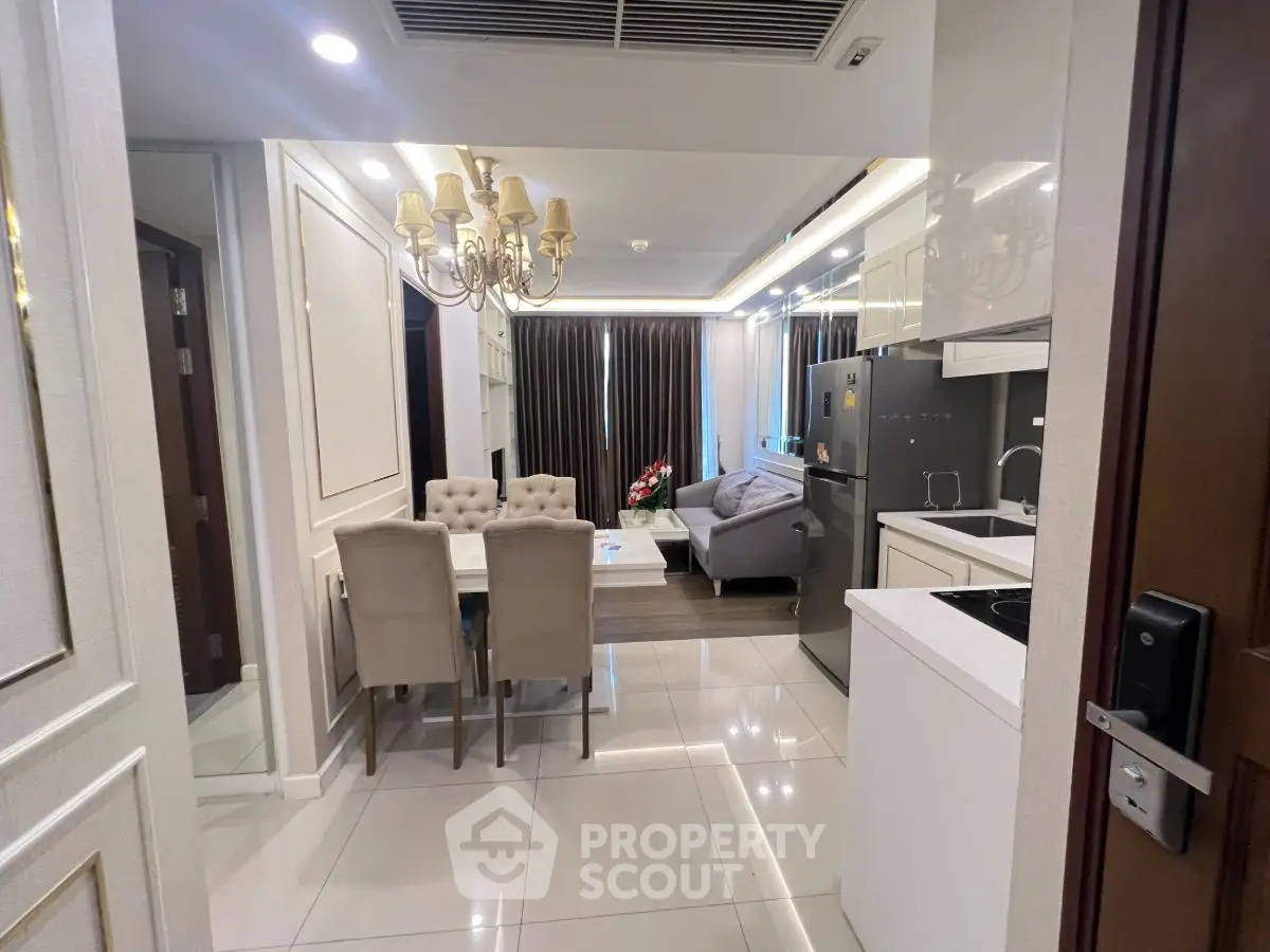 Luxurious open-plan living room and kitchen with elegant chandelier and modern appliances.