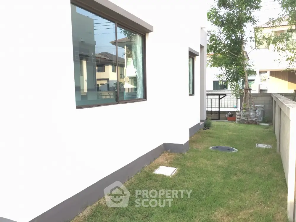 Modern residential exterior with lush green lawn and large windows