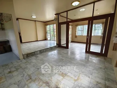 Spacious open-plan living area with marble flooring and large windows.