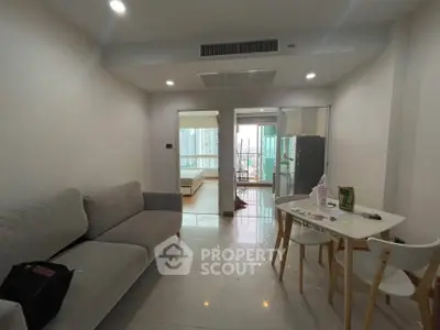 Modern apartment interior with cozy living room and dining area, featuring a view into the bedroom.