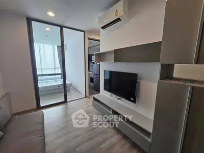 Modern living room with sleek design and air conditioning, featuring a view into a cozy bedroom.