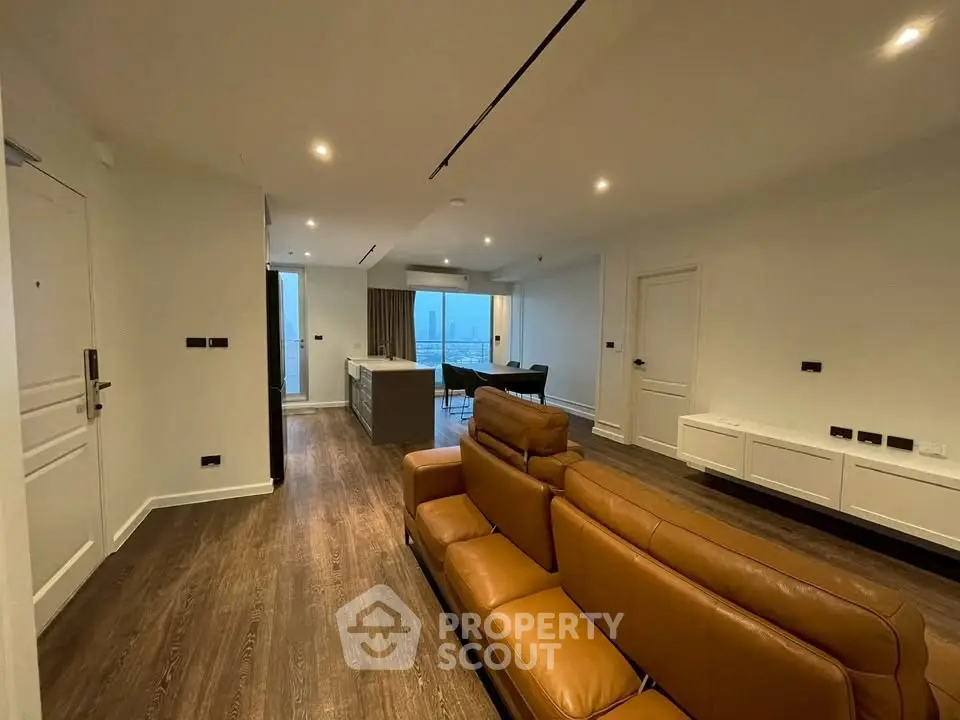 Spacious modern living room with leather sofa and open kitchen layout