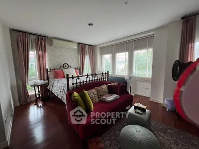 Charming bedroom with elegant decor and large windows offering natural light and garden views.