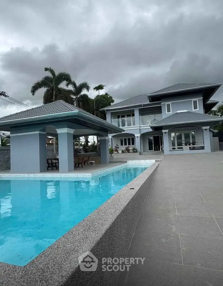 Luxurious modern villa with private pool and spacious outdoor area under cloudy skies.