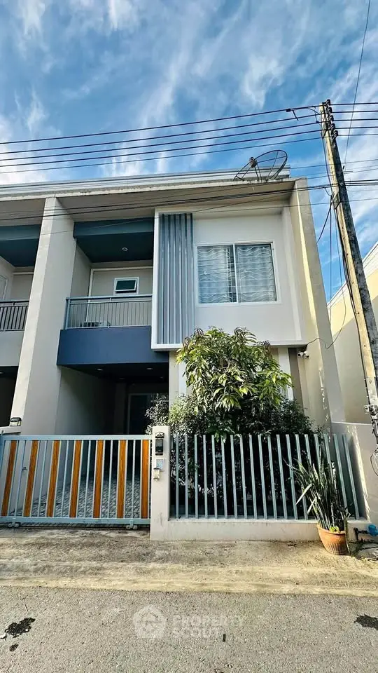 Modern townhouse exterior with sleek design and gated entrance under a clear blue sky.