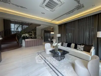 Luxurious living room with elegant decor and modern staircase in a stylish home.