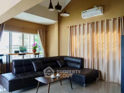Modern living room with stylish leather sofa and large window offering natural light.