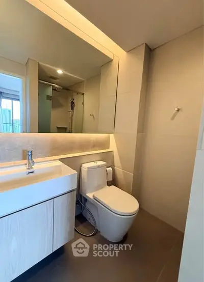 Modern bathroom with sleek fixtures and large mirror in a contemporary apartment.