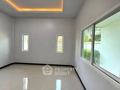 Spacious empty room with large windows and modern ceiling lighting, perfect for customization.