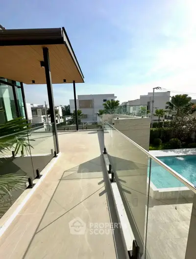 Luxurious modern balcony with glass railing and pool view in upscale neighborhood.