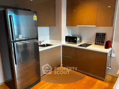 Modern kitchen with sleek cabinetry, stainless steel fridge, and compact appliances in a cozy apartment.