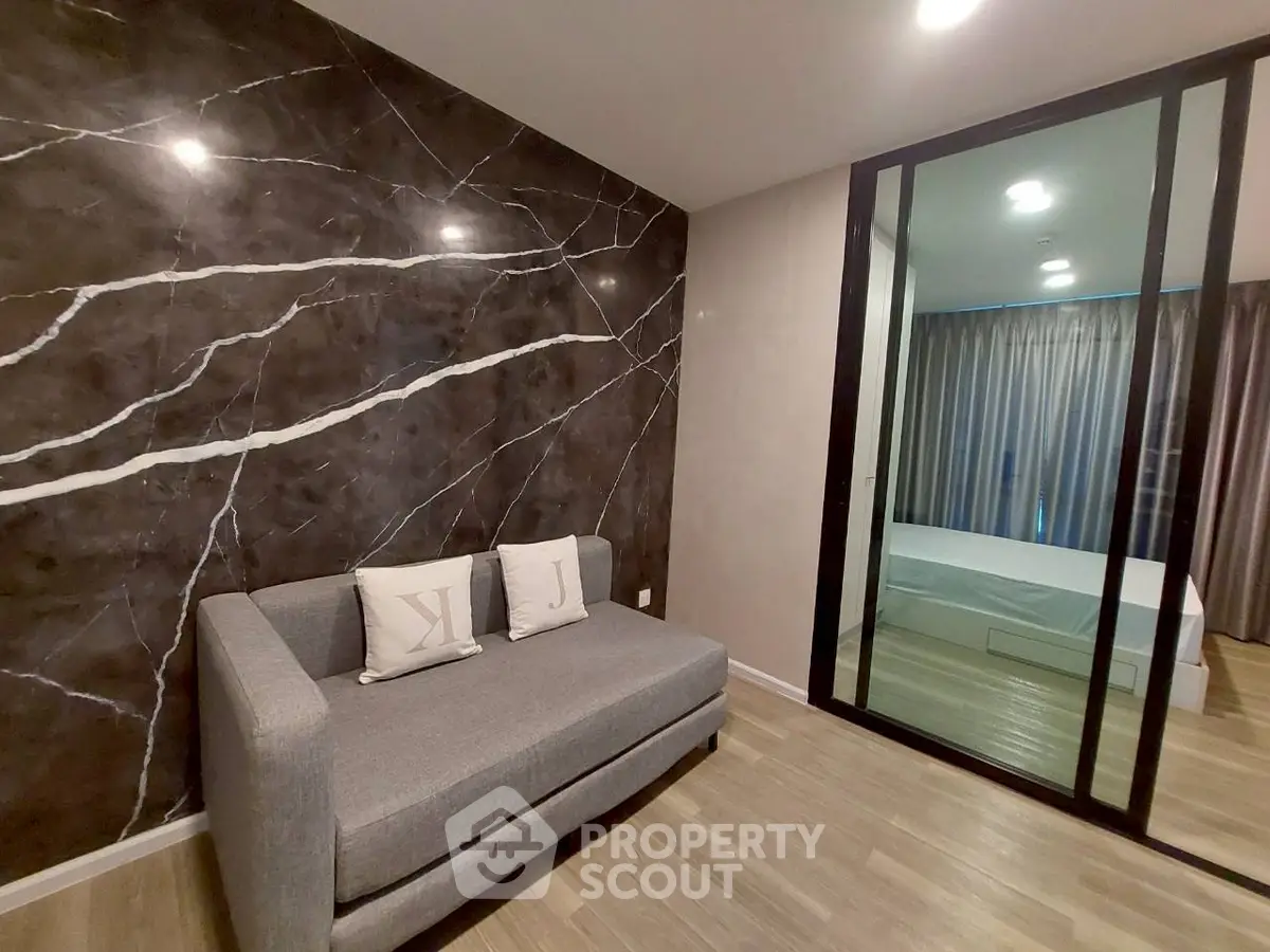 Modern living room with stylish marble accent wall and cozy gray sofa
