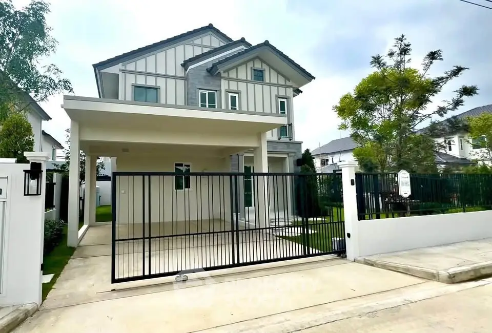 Modern two-story house with gated driveway and lush greenery in a serene neighborhood.
