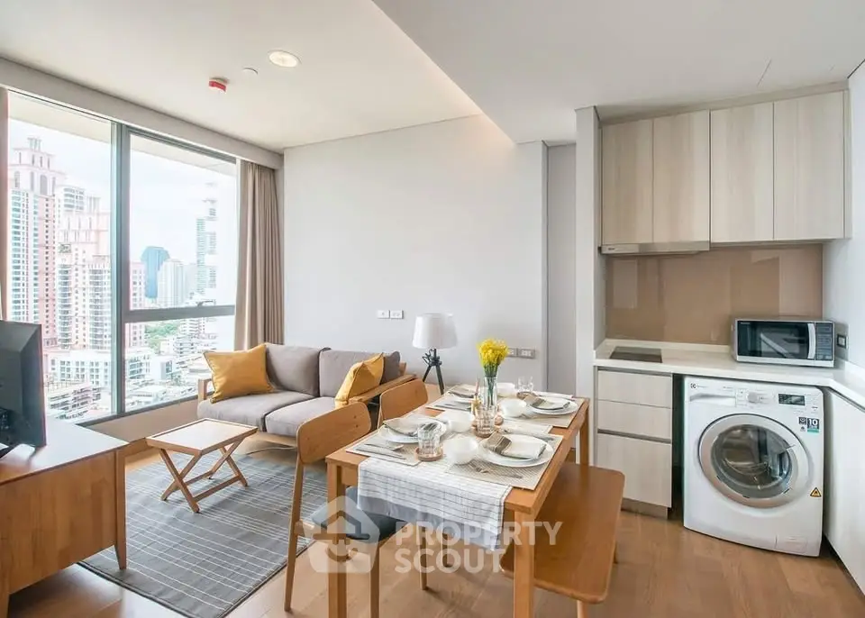 Modern living room with city view, cozy seating, dining area, and compact kitchen with washing machine.