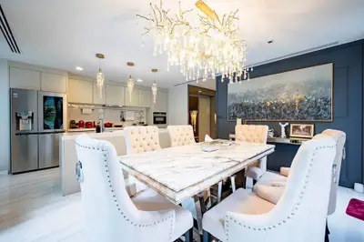 Luxurious dining area with elegant chandelier and modern kitchen in open layout design.