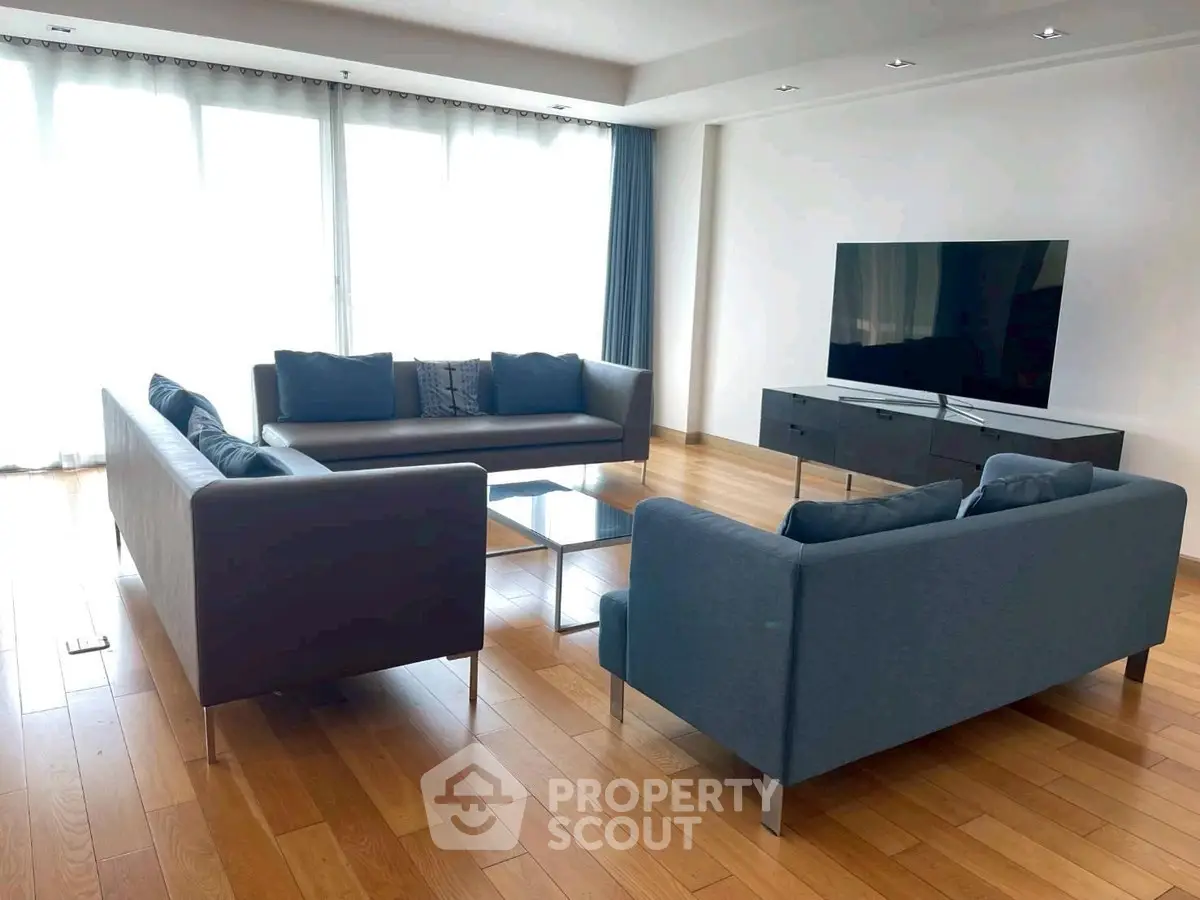 Spacious living room with modern sofas and large TV, perfect for relaxation.