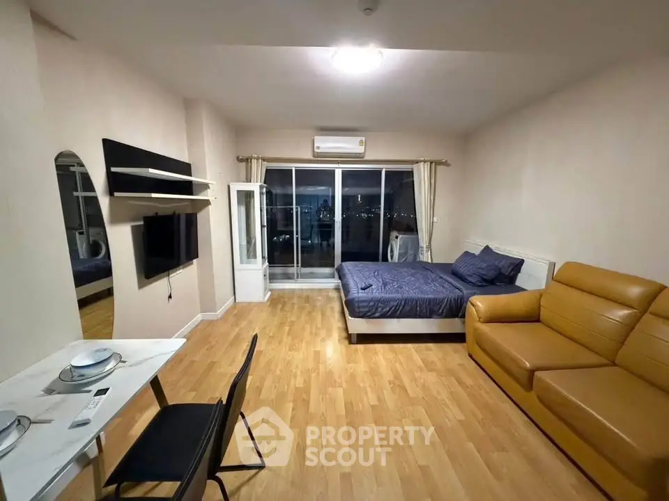 Modern studio apartment with wooden flooring, cozy bed, and stylish furniture, offering a comfortable living space.